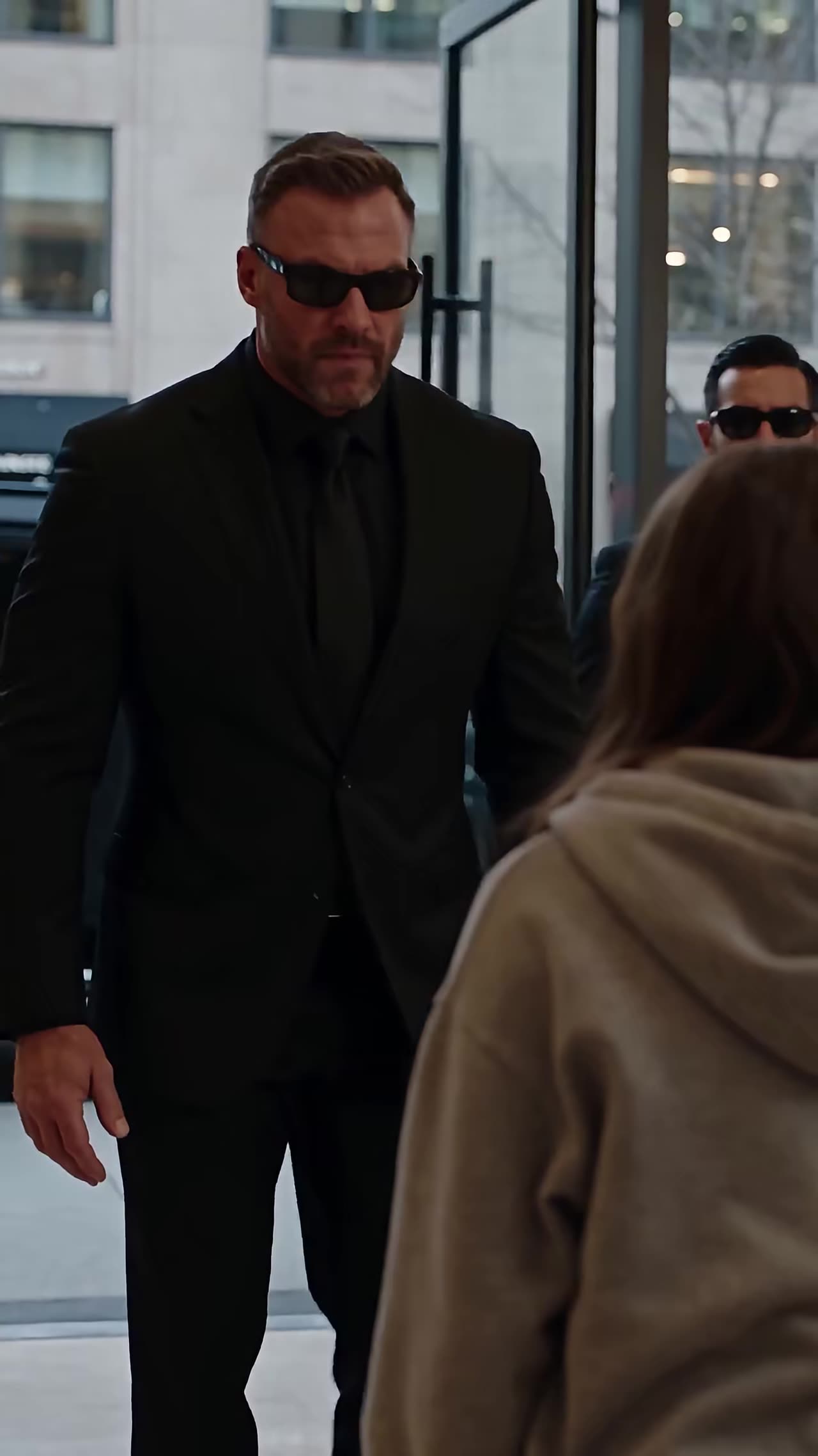 Bodyguard in black suit approaching hoodie-clad girl