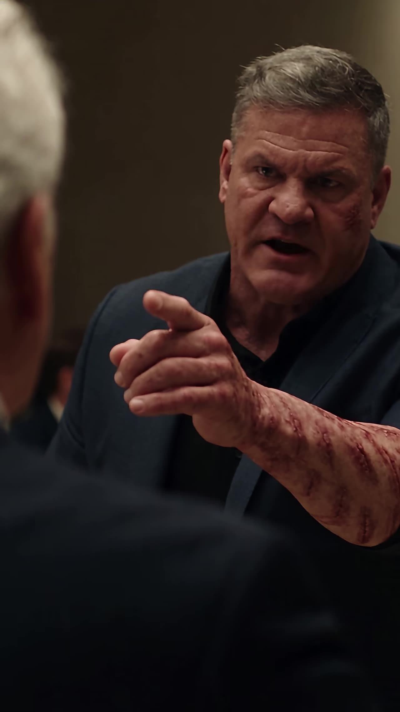 Scarred veteran pointing angrily as he defends the pilot