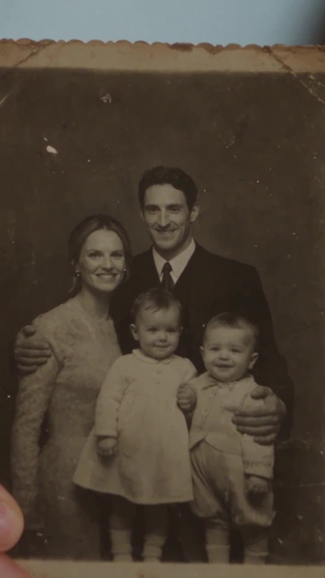 A vintage faded family photograph of a smiling couple and their twin baby daughters.