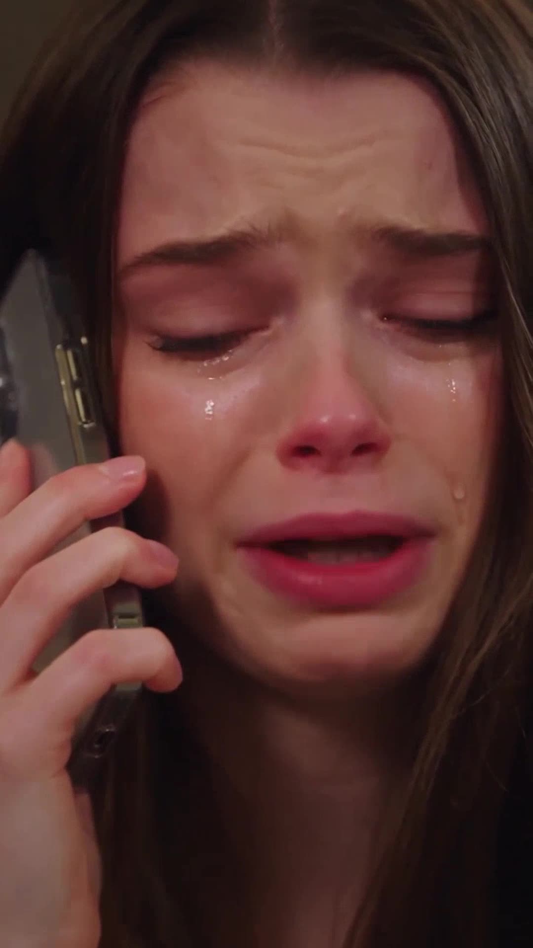 Young brown-haired woman crying desperately on her phone in the hotel lobby