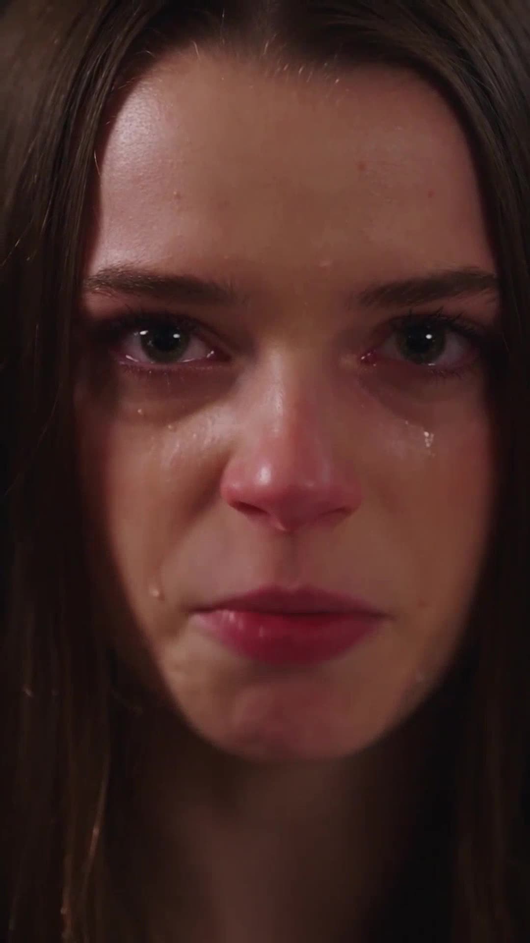 Extreme close-up of a tearful young woman looking intensely forward with fiery determination