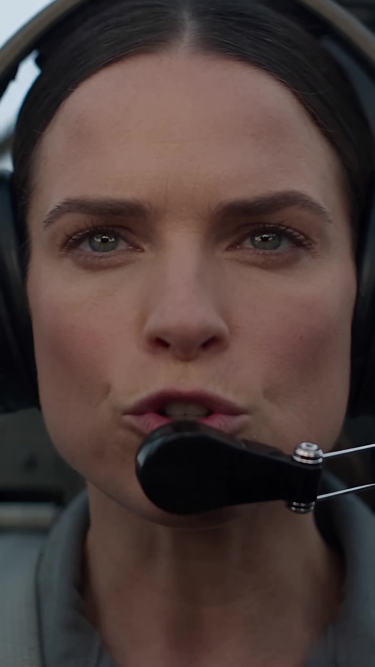 Close-up of determined woman in cockpit speaking into headset