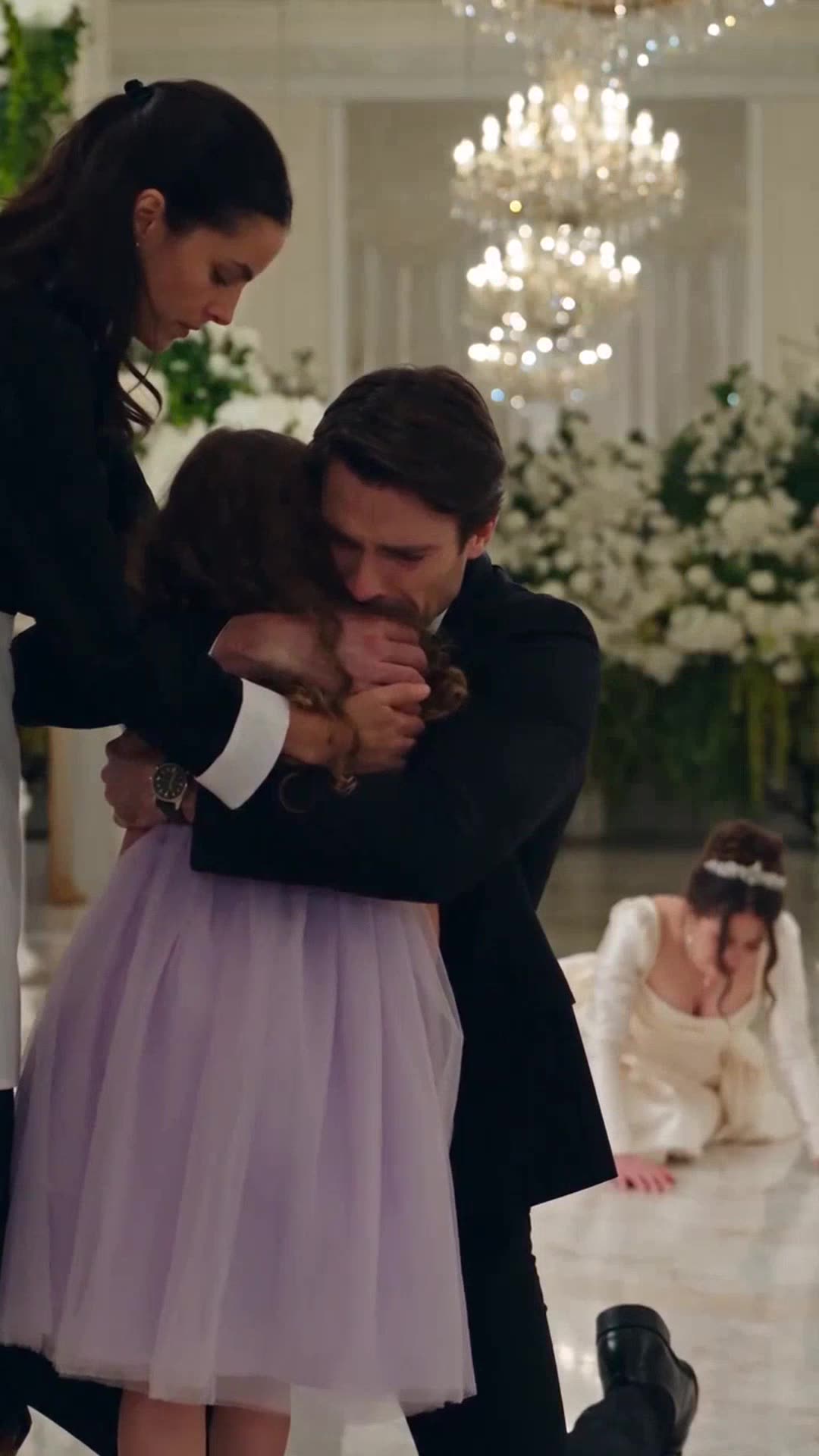 Julien kneels down in tears embracing his niece Léa while Sabrina lies defeated on the floor behind them.
